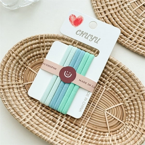 Detailed view of high-elastic seamless green hair ties on a natural rattan tray