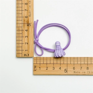 Détail d'un chouchou de badminton violet avec un pendentif volant de 2cm sur une règle