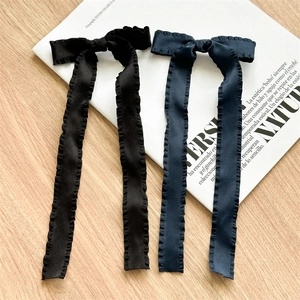 Detail of pleated ribbon bow hair clips in black and navy blue on a wooden surface