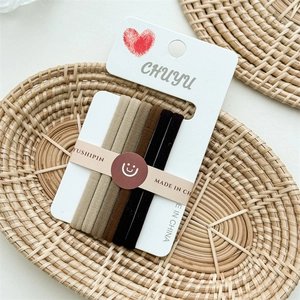 Detailed view of 5 seamless elastic hair ties in earth tones on a white display card