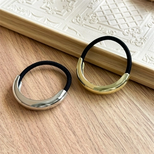 Close-up of gold and silver minimalist alloy hair rings with black elastic bands on wood