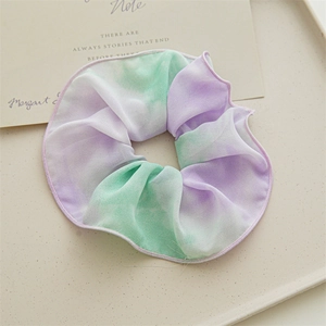 Vue détaillée d'un chouchou tie-dye violet et vert sur un plateau décoratif