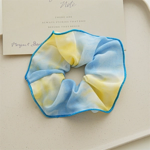 Gros plan d'un chouchou tie-dye bleu et jaune avec bordures surjetées sur un plateau déco