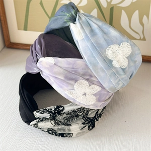 Close-up of four wide floral and tie-dye headbands with lace detailing and soft fabric texture