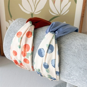 Set of twisted wide headbands with fresh fruit patterns and solid colors on a display stand