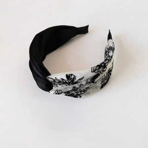 Elegant wide floral headband featuring black satin and white mesh fabric in a twisted design