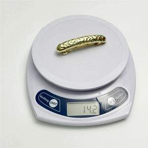 Detailed view of the gold geometric metal hair clip weighing 14.2g on a scale