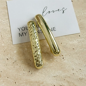 Detailed view of two gold metal hair clips with hammered and smooth polished textures