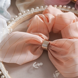 Gros plan sur chouchou nœud rose avec boucle dorée et rayures métallisées brillantes