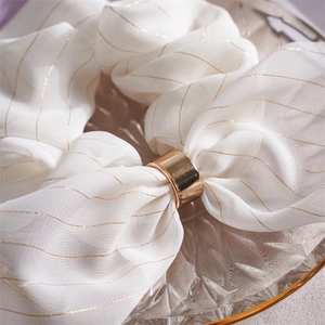 Détail d'une boucle en métal doré élégante avec ruban en soie blanc et rayures dorées