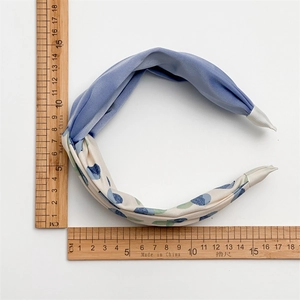 Blue and polka dot fabric headband with twisted cross design shown with scale measurements