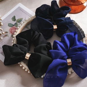 Détail de chouchous à nœud élégants avec boucles dorées sur un plateau de perles