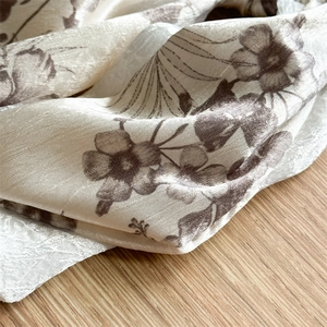 Close-up of floral satin fabric with brown vintage patterns and fine stitching detail