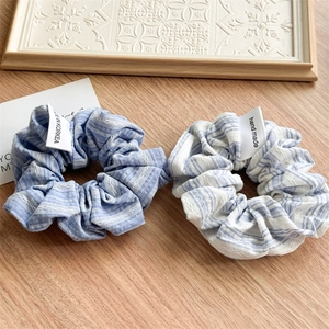 Close-up of blue and white striped fabric scrunchies with handmade woven labels