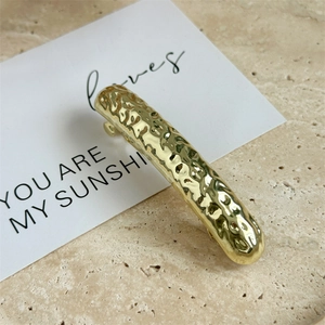 Macro shot of gold metal hair clip featuring a refined hammered texture and curved design