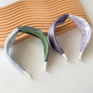 Detail view of satin twist headbands in tie-dye blue and lilac with floral embroidery