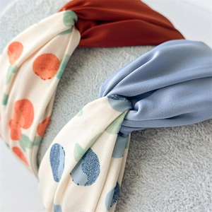 Close-up of three twisted fabric headbands with floral prints and solid colors