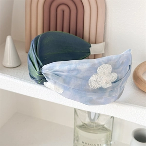 Detail of wide pleated headband in iridescent blue-green with white lace floral applique