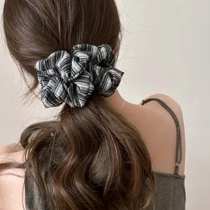Detailed texture of large striped fabric scrunchie worn on a high ponytail for hair styling