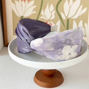 Detail of vintage wide headband featuring purple tie-dye silk fabric and white lace floral patch