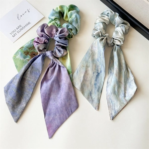 Close-up of three watercolor oil painting style scrunchies with flowing silk ribbons
