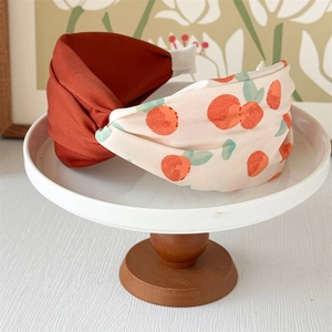 Close-up of a wide twisted headband with orange print and caramel satin fabric detail