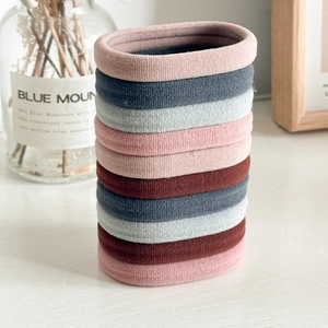 Elastic ribbed hair ties in milk coffee colors stacked with a glass vase backdrop