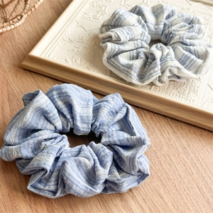 Close-up of blue and white striped fabric scrunchies on a vintage white tray and wood background