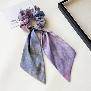 Detail of artistic lavender and blue gradient silk ribbon scrunchie on a white tray