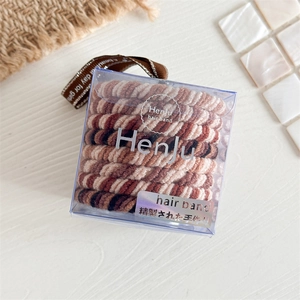Set aus spiralförmigen Haargummis in Braun und Beige in einer transparenten Acrylbox