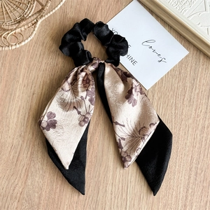 Detailed shot of double-layered floral satin bow scrunchie with long ribbons