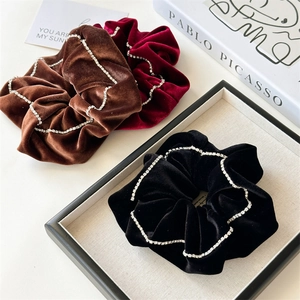 Detailed close-up of velvet hair scrunchies with rhinestone edges in various colors