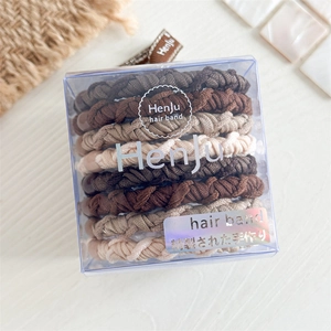 Detail von gewebten elastischen Haarbändern in Braun und Beige in einer Klarsichtbox