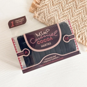 Detail of 10-piece black elastic hair ties set in clear window box on wooden desk