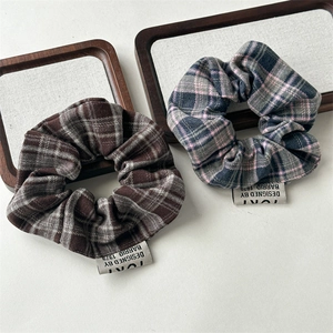 Close-up of vintage plaid scrunchies with woven texture and brand labels on wooden frames