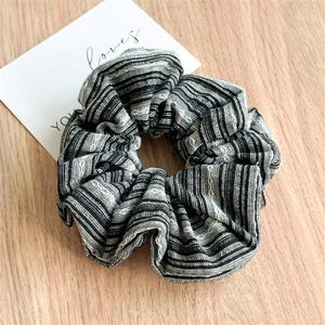 Detailed view of black and white striped scrunchie on a minimalist wooden background