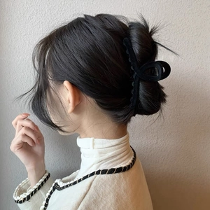Dettaglio di un grande fermaglio per capelli nero floccato che fissa uno chignon da donna