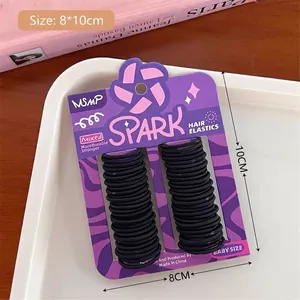 Dettaglio di elastici per capelli neri per neonati su carta viola in un vassoio bianco