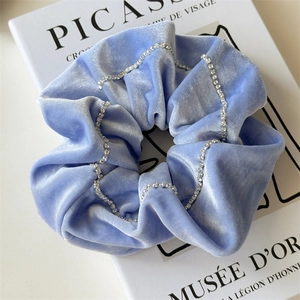 Detail of light blue velvet hair scrunchie with sparkling rhinestone chain on art book