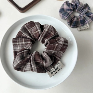 Close-up of vintage plaid scrunchie with designer label inside a white ceramic dish