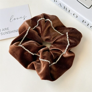 Macro shot of brown velvet scrunchie with rhinestones on a white aesthetic background