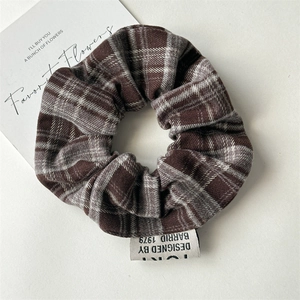 Close-up of vintage plaid hair scrunchie with classic brown grid and woven label detail