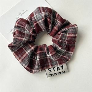 Detail of red and grey plaid scrunchie with woven label on soft textured fabric