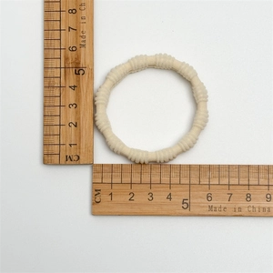 Gros plan d'un chouchou beige élastique de 5 cm mesuré avec une règle graduée