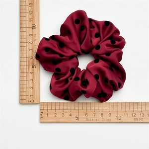 Detail view of a burgundy polka dot scrunchie with rulers showing the 11cm diameter size