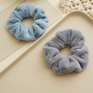 Dettaglio di elastici per capelli in peluche azzurro e grigio su un vassoio beige