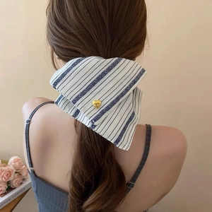 Close-up of blue striped fabric bow hair accessory with a gold heart detail on model
