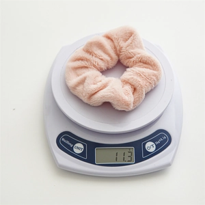 Dettaglio di un elastico per capelli in peluche rosa del peso di 11,3 g sulla bilancia