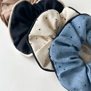 Detailed view of layered fabric scrunchies in brown, black, white and blue with dots