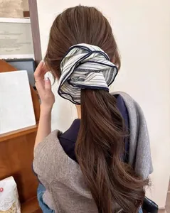 Close-up of a blue and white striped silk scrunchie on a ponytail with a vintage look